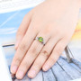 peridot and white zircon leaf motif ring in rhodium over sterling silver worn on a hand