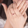 ruby and diamond infinity design ring in 14k rose gold worn on a hand