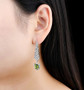 designer peridot and zircon dangle earrings in rhodium over sterling silver worn on the ear