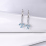 sky blue topaz heart dangle earrings in rhodium over sterling silver shown in a lifestyle photo