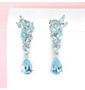 sky blue topaz dangle earrings in rhodium over sterling silver shown in a lifestyle photo