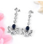 sapphire and white zircon dangle earrings in rhodium over sterling silver shown in a lifestyle photo