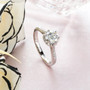 moissanite round heart side gallery ring in rhodium over sterling silver shown in a lifestyle photo