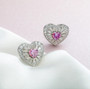 pink moissanite heart halo stud earrings in rhodium over sterling silver shown in a lifestyle photo