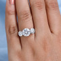 moissanite round trilogy ring in rhodium over sterling silver worn on a hand