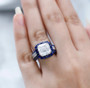 asscher cut moissanite and sapphire halo ring in rhodium over sterling silver worn on a hand