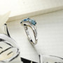 side view of london sky blue topaz and white zircon rhodium over sterling silver bypass ring