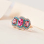 pink tourmaline blue apatite and moissanite trilogy halo ring in 18k rose gold over sterling silver shown in a lifestyle photo