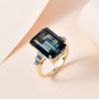 london blue emerald cut topaz blue diamond and white diamond ring in 10k yellow gold shown in a lifestyle photo