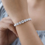 round moissanite tennis bracelet in rhodium over sterling silver worn on a wrist