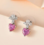 pink and white moissanite heart dangle earrings in rhodium over sterling silver shown in a lifestyle photo