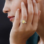 yellow diamond white diamond and alexandrite halo ring in 18k yellow gold worn on a hand