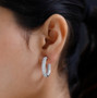 white zircon inside out hoop earrings in rhodium over sterling silver worn on the ear