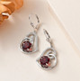 garnet and moissanite heart dangle earrings in rhodium over sterling silver shown in a lifestyle photo