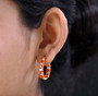 fire opal and moissanite hoop earrings in 18k yellow gold over sterling silver worn on the ear
