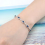 sapphire and white zircon halo bracelet in rhodium over sterling silver worn on a wrist
