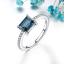 london blue topaz white zircon and emerald cut solitaire ring in rhodium over sterling silver shown in a lifestyle photo