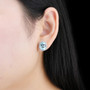 sky blue topaz and white zircon oval halo stud earrings in rhodium over sterling silver worn on the ear