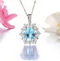 close up of sky blue topaz and white zircon halo pendant necklace in rhodium over sterling silver