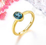 london blue topaz oval bezel set solitaire ring in 18k yellow gold over sterling silver shown in a lifestyle photo