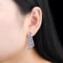 tanzanite and white zircon dangle earrings in rhodium over sterling silver worn on the ear