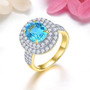 swiss blue topaz and white zircon double halo ring in 18k yellow gold over sterling silver shown in a lifestyle photo