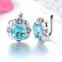 side view of sky blue topaz tanzanite and white zircon halo earrings in rhodium over sterling silver