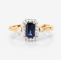 full view of emerald cut blue sapphire and white diamond halo ring in 14k yellow gold
