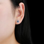 blue sapphire and white zircon halo stud earrings in rhodium over sterling silver worn on the ear