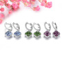 close up of tanzanite and white zircon cluster halo earrings in rhodium over sterling silver