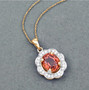 close up of orange sapphire and diamond halo pendant necklace in solid 14k yellow gold