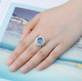 london blue topaz and white zircon double halo ring in rhodium over sterling silver worn on a hand