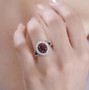 garnet and white zircon halo ring in 18k yellow gold over sterling silver worn on a hand