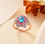 blue apatite pink sapphire and white zircon floral halo ring in 18k rose gold over sterling silver shown in a lifestyle photo