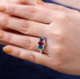 rubellite tourmaline indicolite tourmaline and moissanite three stone halo ring in rhodium over sterling silver worn on a hand