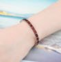emerald cut garnet tennis bracelet in rhodium over sterling silver worn on a wrist
