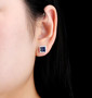 blue sapphire and white zircon halo stud earrings in rhodium over sterling silver worn on the ear
