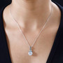 moissanite and green sapphire pendant necklace in rhodium over sterling silver worn around the neck