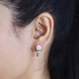moissanite and green sapphire earrings in rhodium over sterling silver worn on the ear