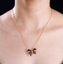 garnet and white zircon bow necklace in 18k yellow gold over sterling silver worn around the neck