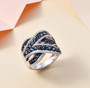 blue sapphire and moissanite crossover ring in rhodium over sterling silver shown in a lifestyle photo