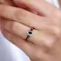 indicolite tourmaline and moissanite three stone ring in 18k yellow gold over sterling silver worn on a hand
