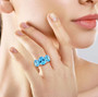 swiss blue topaz trilogy ring in rhodium over sterling silver worn on a hand
