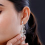 cubic zirconia articulating chandelier earrings in rhodium over sterling silver worn on the ear