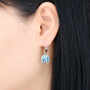sky blue topaz dangle earrings in rhodium over sterling silver worn on the ear