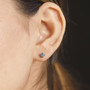 round lab grown blue diamond stud earrings in rhodium over sterling silver worn on the ear