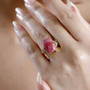 thulite and white zircon ring in 18k yellow gold over sterling silver worn on a hand