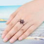 garnet and white zircon flower cluster ring in rhodium over sterling silver worn on a hand