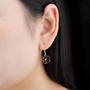 garnet and white zircon flower cluster earrings in rhodium over sterling silver worn on the ear