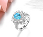 close up of swiss or sky blue topaz and white zircon halo cluster ring in rhodium over sterling silver